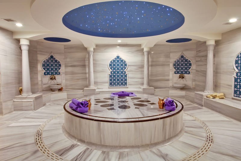 Salle de marbre d'un hammam à Istanbul avec göbek taşı central, plafond étoilé et décoration ottomane