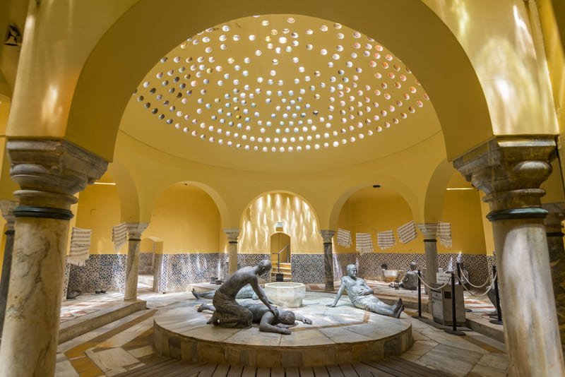 Intérieur d'un hammam historique d'Istanbul avec statues ottomanes représentant le rituel du bain turc et coupole à claustra lumineuse