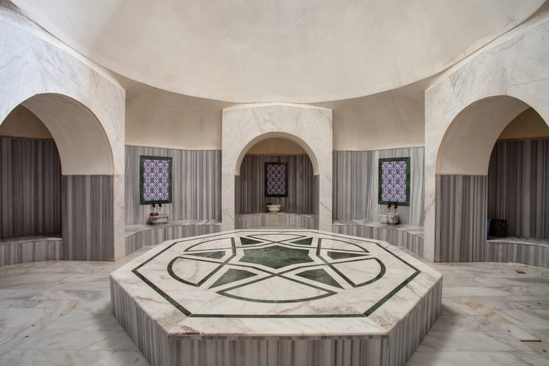 Salle intérieure d'un hammam traditionnel à Istanbul avec göbek taşı octogonal en marbre et arches ottomanes
